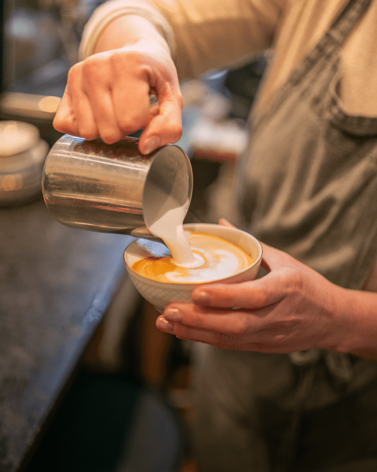 Mousse de lait versée dans un latte fait maison à La Tasse, café écoresponsable à Uccle