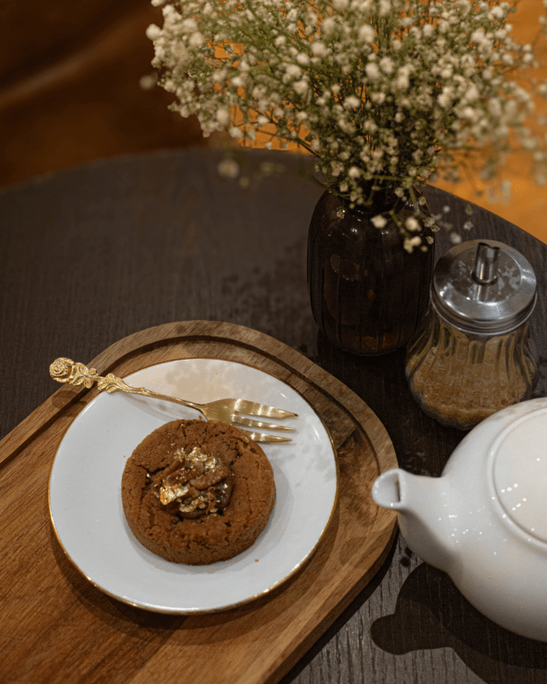 Cookie au chocolat sur plateau en bois avec théière blanche, fleur séchée et ambiance cosy