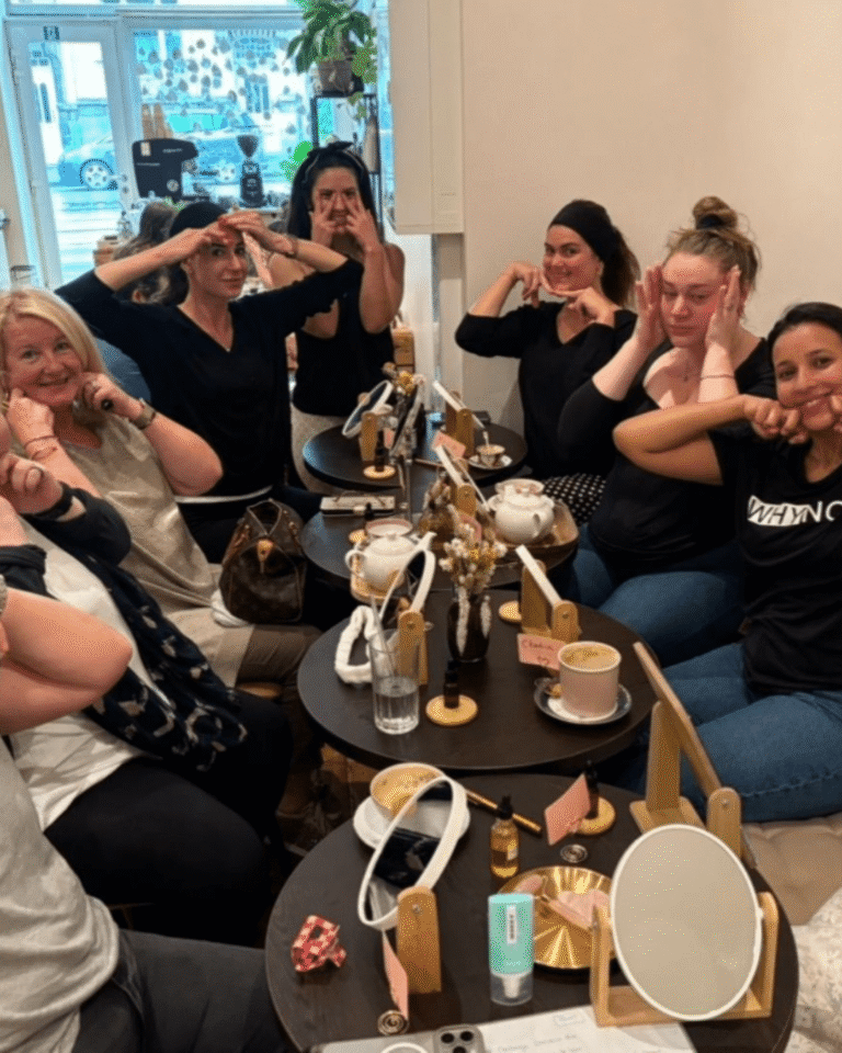 Groupe de femmes en pleine séance de face yoga autour de tasses de thé.