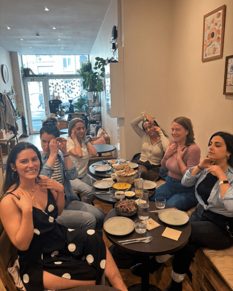 Participantes à un atelier Face Yoga Gourmand effectuant des mouvements du visage après un brunch.